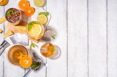 Modaya uygun çay seti yeşil, oolong, siyah, çay ve diğer çay karışımlarından esinlenilmiştir. Soda, şerbetli soğuk yaz içecekleri, limon, kireç ve nane, güneşli beyaz ahşap arka plan.