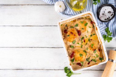 Evlen benimle tavuk, fırında tavuk budu, kremalı domates sosu, güneşte kurutulmuş domates, parmesan peyniri ve sert krema ile modaya uygun tavuk eti tarifi, ahşap ahşap masa ve yemek malzemeleri.