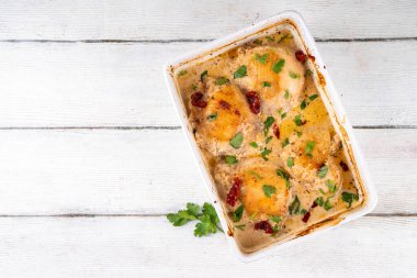 Evlen benimle tavuk, fırında tavuk budu, kremalı domates sosu, güneşte kurutulmuş domates, parmesan peyniri ve sert krema ile modaya uygun tavuk eti tarifi, ahşap ahşap masa ve yemek malzemeleri.