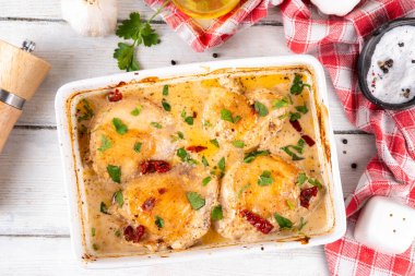 Evlen benimle tavuk, fırında tavuk budu, kremalı domates sosu, güneşte kurutulmuş domates, parmesan peyniri ve sert krema ile modaya uygun tavuk eti tarifi, ahşap ahşap masa ve yemek malzemeleri.