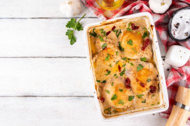 Evlen benimle tavuk, fırında tavuk budu, kremalı domates sosu, güneşte kurutulmuş domates, parmesan peyniri ve sert krema ile modaya uygun tavuk eti tarifi, ahşap ahşap masa ve yemek malzemeleri.