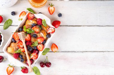 Yaz meyvesi ve Fransız tostu fırınlanmış güveç. Ev yapımı lezzetli Fransız tostu, kremalı kahvaltı pastası, kızarmış ekmek ve taze çilek, yabanmersini, ahududu ve kirazlı.