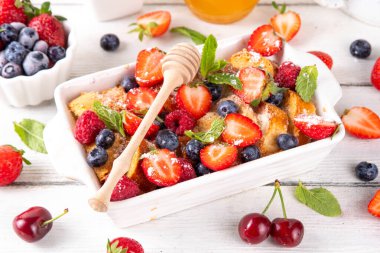 Yaz meyvesi ve Fransız tostu fırınlanmış güveç. Ev yapımı lezzetli Fransız tostu, kremalı kahvaltı pastası, kızarmış ekmek ve taze çilek, yabanmersini, ahududu ve kirazlı.