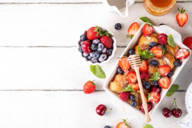 Yaz meyvesi ve Fransız tostu fırınlanmış güveç. Ev yapımı lezzetli Fransız tostu, kremalı kahvaltı pastası, kızarmış ekmek ve taze çilek, yabanmersini, ahududu ve kirazlı.