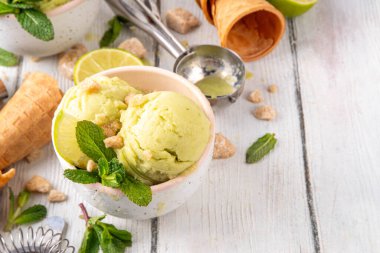 Yaz ferahlatıcı soğuk tatlı, lezzetli aromatik mojito veya limonlu turtalı dondurma, seramik kasede mojito kokteyli aromalı ev yapımı şerbet, taze limon, nane, ahşap zemin üzerinde waffle konileri.