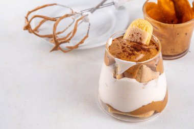 Moda dalgona tiramisu tatlısı. İki bardak kremalı kremalı kahve tiramisu, üzerine de hazır kahve köpüğü ve savoyardi.