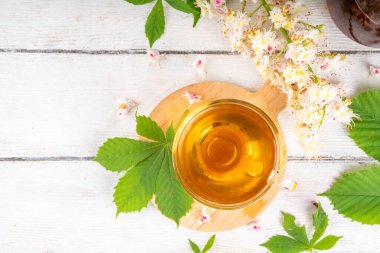 Organik doğal kestane yaprakları ve çiçek çayı. Sıcak alternatif kafeinsiz bitkisel içecek, lezzetli sağlıklı içecek, beyaz ahşap arka planda fotokopi alanı.