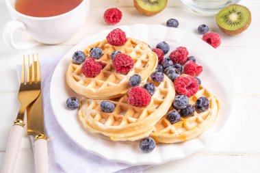 Beyaz ahşap masadaki böğürtlenli ev yapımı Belçika waffle 'ları lezzetli brunch' lar ya da Belçika waffle 'ları.