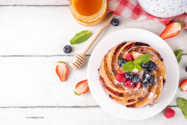Taze meyve ve böğürtlenli yaz pastası. Geleneksel yuvarlak sünger keki, çilekli mevsimlik tatlı, ahududu, yabanmersini, bal ve şeker serpintileri, beyaz ahşap masa fotokopisi alanı