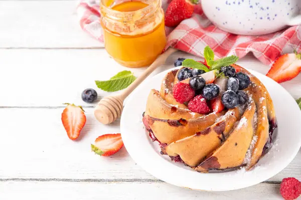 Taze meyve ve böğürtlenli yaz pastası. Geleneksel yuvarlak sünger keki, çilekli mevsimlik tatlı, ahududu, yabanmersini, bal ve şeker serpintileri, beyaz ahşap masa fotokopisi alanı