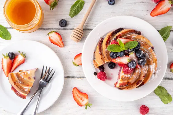 Taze meyve ve böğürtlenli yaz pastası. Geleneksel yuvarlak sünger keki, çilekli mevsimlik tatlı, ahududu, yabanmersini, bal ve şeker serpintileri, beyaz ahşap masa fotokopisi alanı