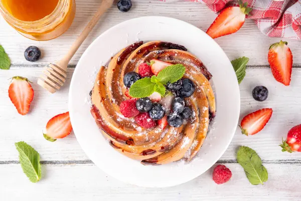 Taze meyve ve böğürtlenli yaz pastası. Geleneksel yuvarlak sünger keki, çilekli mevsimlik tatlı, ahududu, yabanmersini, bal ve şeker serpintileri, beyaz ahşap masa fotokopisi alanı