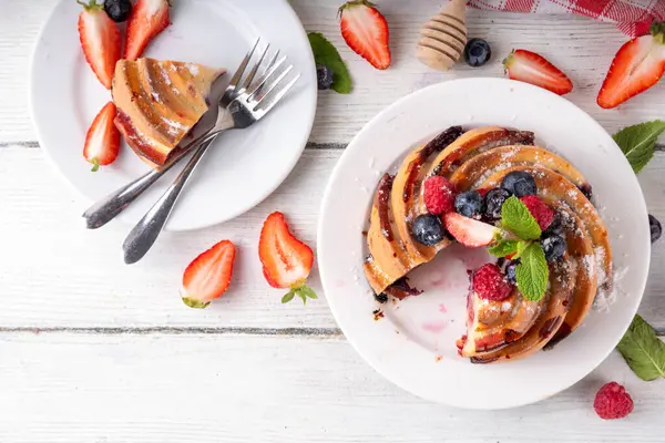 Taze meyve ve böğürtlenli yaz pastası. Geleneksel yuvarlak sünger keki, çilekli mevsimlik tatlı, ahududu, yabanmersini, bal ve şeker serpintileri, beyaz ahşap masa fotokopisi alanı