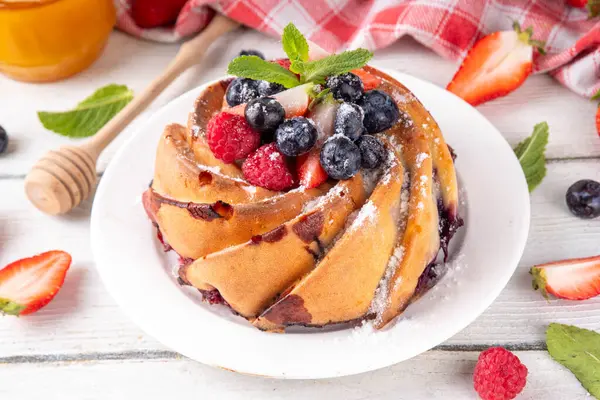Taze meyve ve böğürtlenli yaz pastası. Geleneksel yuvarlak sünger keki, çilekli mevsimlik tatlı, ahududu, yabanmersini, bal ve şeker serpintileri, beyaz ahşap masa fotokopisi alanı