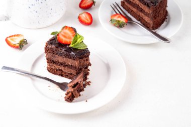 Koyu çikolatalı pasta dilimleri, çikolatalı krema ve çilekli, porsiyonlu tabaklarda, kopyalama alanı