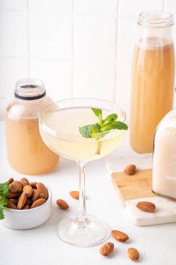 Tatlı ve ekşi limon orgeat kokteyli, Orgeat limonata tarifi, bir martini bardağı alkollü içki ve badem şurubu şişesi.