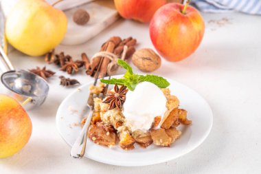  Elmalı gevrek tatlı, dondurmalı çıtır tart, kıtır kıtır hamurlu turta fırın tabağında ve tabakta, dondurma kepçesiyle beyaz mutfak masasında.