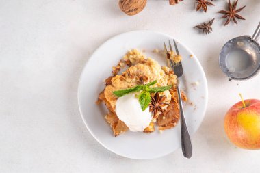  Elmalı gevrek tatlı, dondurmalı çıtır tart, kıtır kıtır hamurlu turta fırın tabağında ve tabakta, dondurma kepçesiyle beyaz mutfak masasında.