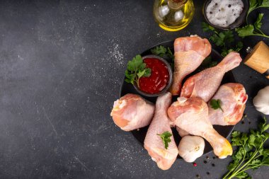 Tavuk eti hazırlama arka planı, ızgaraya hazır çiğ tavuk bacağı, baharatlar, tuz, biber, zeytinyağı, sarımsak ve salamura veya sos. Izgara ve bbq sezon pişirme arka planı, kopyalama alanı