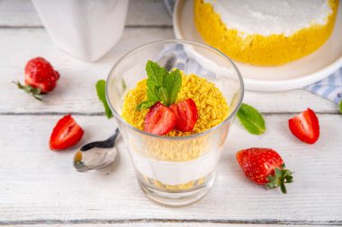 Klasik cam kaplı cheesecake, taze çilekli ve altın kurabiyeli. Katmanlı cheesecake tatlısıyla beyaz ahşap masa üzerinde taze çilekler fotokopi alanı