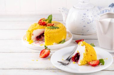 Tepetaklak Pasta yok, klasik Cheesecake New York 'un viral modası altın kurabiye parçacıkları, beyaz krem peynir ve böğürtlen reçeli katmanları, taze çilek ve ahşap masa üzerinde nane