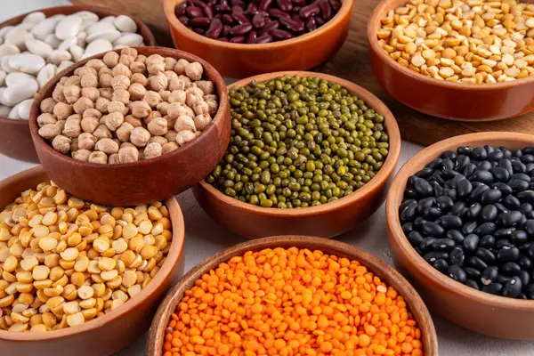 Çeşitli kuru fasulyeler, mercimek, mung, nohut, ahşap kaselerde bezelye çeşitleri. Legumes beyaz masa üst görünümünde. Vegan protein kaynakları yiyecek, kopyalama alanı