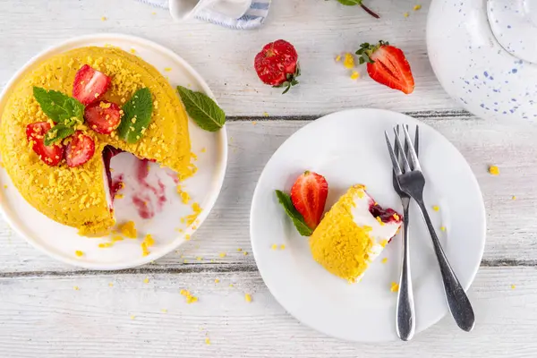 Tepetaklak Pasta yok, klasik Cheesecake New York 'un viral modası altın kurabiye parçacıkları, beyaz krem peynir ve böğürtlen reçeli katmanları, taze çilek ve ahşap masa üzerinde nane