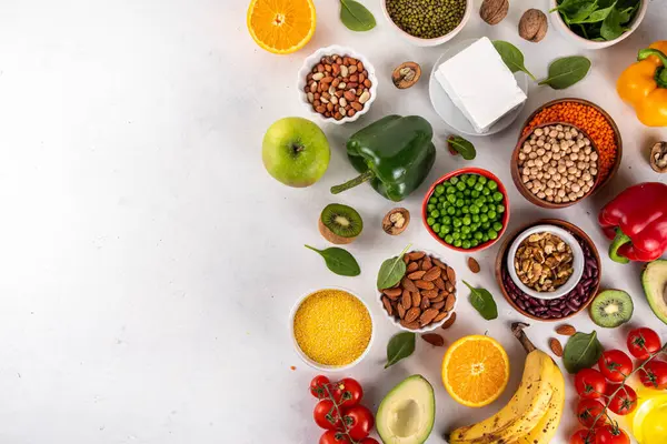 Portföy diyeti, fındık, sebze proteini, bitki sterolleri, yapışkan lif, fasulye, baklagiller, taze sebzeler ve beyaz arka plandaki meyveler dahil olmak üzere dengeli kolesterol vejetaryen gıdalar.