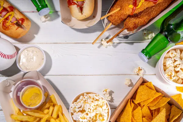 Geleneksel spor stadyumu yemekleri ve bira arka planı, çeşitli beyzbol, basketbol, futbol fanatikleri ve stadyum atıştırmalıkları, cips, sos, bira şişeli sosisliler ve fan aksesuarları. 