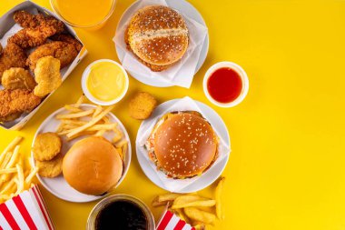 Fast food servis menüsünde çeşitli hamburgerler, cheeseburger, nugget, patates kızartması, gazlı içecek. Ivır zıvır sağlıksız fast food, düşük besinli Ultra işlenmiş gıda, yüksek kalori değeri