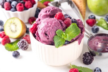 Ev yapımı meyve ve meyveli dondurma, sağlıklı meyve ve yoğurt ile porsiyonlu dondurma taze yaban mersini, ahududu, çilek, böğürtlen, elmalar, mutfak masasında kivi.