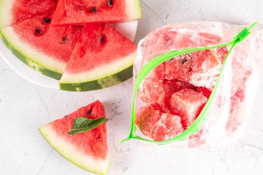 Donmuş karpuz dilimleri, donmuş poşetlerdeki taze çiğ karpuzlar mutfak masasındaki beyaz masa, sağlıklı basit konserve, kış konsepti için dondurulmuş meyve hasadı stokları.. 