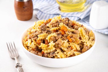 Kıymalı ev yapımı makarna. Biftek ve sonbahar sebzeli bir çömlek makarna, mutfak masasında porsiyonlu tabakta.