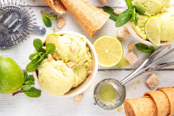 Yaz ferahlatıcı soğuk tatlı, lezzetli aromatik mojito veya limonlu turtalı dondurma, seramik kasede mojito kokteyli aromalı ev yapımı şerbet, taze limon, nane, ahşap zemin üzerinde waffle konileri.