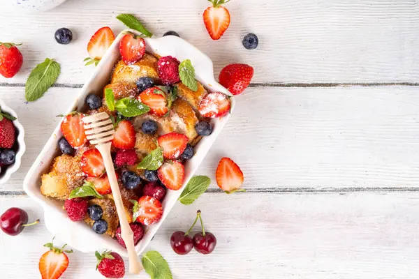 Yaz meyvesi ve Fransız tostu fırınlanmış güveç. Ev yapımı lezzetli Fransız tostu, kremalı kahvaltı pastası, kızarmış ekmek ve taze çilek, yabanmersini, ahududu ve kirazlı.