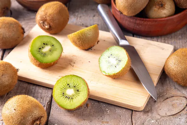 Tatlı kivi meyveleri, bütün ve dilimlenmiş, mutfak masasının üzerinde fotokopi alanı. Yeşil ve altın kivi çeşitleri 