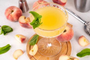 Düz şeftalili martini ya da margarita limonata soğuk meyve suyu, nane ve limonlu yaz meyve suyu kokteyli, beyaz masada.