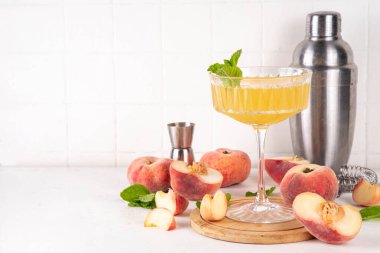 Düz şeftalili martini ya da margarita limonata soğuk meyve suyu, nane ve limonlu yaz meyve suyu kokteyli, beyaz masada.