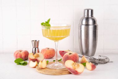 Düz şeftalili martini ya da margarita limonata soğuk meyve suyu, nane ve limonlu yaz meyve suyu kokteyli, beyaz masada.