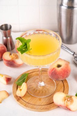 Düz şeftalili martini ya da margarita limonata soğuk meyve suyu, nane ve limonlu yaz meyve suyu kokteyli, beyaz masada.