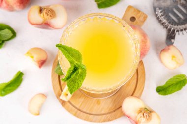 Düz şeftalili martini ya da margarita limonata soğuk meyve suyu, nane ve limonlu yaz meyve suyu kokteyli, beyaz masada.