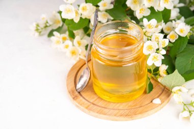 Ev yapımı yasemin çiçeği reçeli, çiçekli altın konserve beyaz masa arkasında taze yasemin çiçekleri