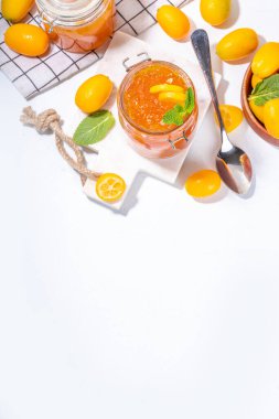 Kumquat jam, homemade citrus tropical fruit marmalade, with fresh kumquat on a white marble table