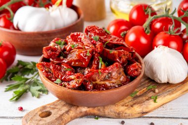 Zeytin yağında ev yapımı kurutulmuş domatesler, gurme İtalyan yemekleri, taze domates, yağ şişesi ve mutfak masasında baharatlar.