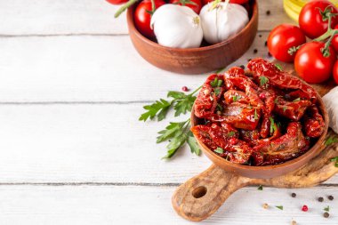 Zeytin yağında ev yapımı kurutulmuş domatesler, gurme İtalyan yemekleri, taze domates, yağ şişesi ve mutfak masasında baharatlar.