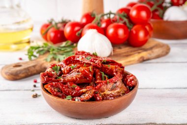 Zeytin yağında ev yapımı kurutulmuş domatesler, gurme İtalyan yemekleri, taze domates, yağ şişesi ve mutfak masasında baharatlar.