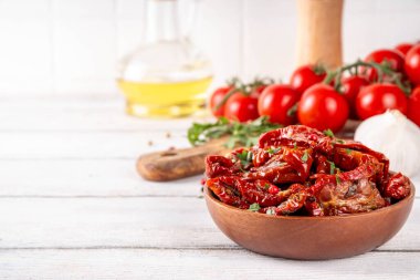 Zeytin yağında ev yapımı kurutulmuş domatesler, gurme İtalyan yemekleri, taze domates, yağ şişesi ve mutfak masasında baharatlar.