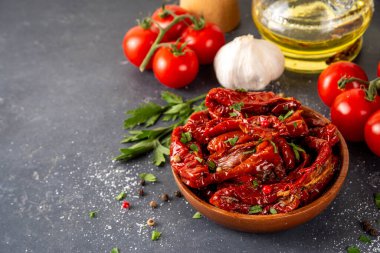 Zeytin yağında ev yapımı kurutulmuş domatesler, gurme İtalyan yemekleri, taze domates, yağ şişesi ve mutfak masasında baharatlar.