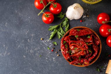 Zeytin yağında ev yapımı kurutulmuş domatesler, gurme İtalyan yemekleri, taze domates, yağ şişesi ve mutfak masasında baharatlar.