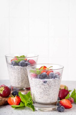 Taze dutlu Chia tohumu pudingi. Sağlıklı yaz kahvaltısı tatlı kremalı süt veya yoğurt, chia, çilek ve yabanmersini, beyaz masa arkaplan fotokopi alanı